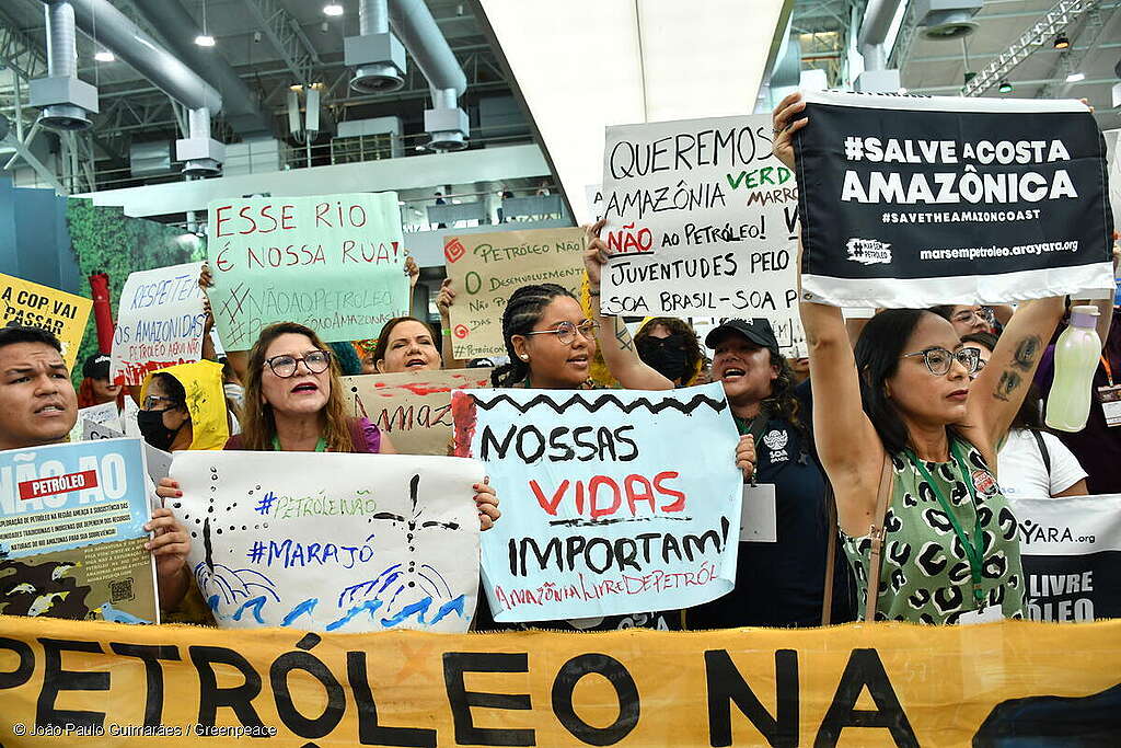Pessoas protestando em uma rua segurando cartazes com frases contra a exploração de petróleo na Amazônia