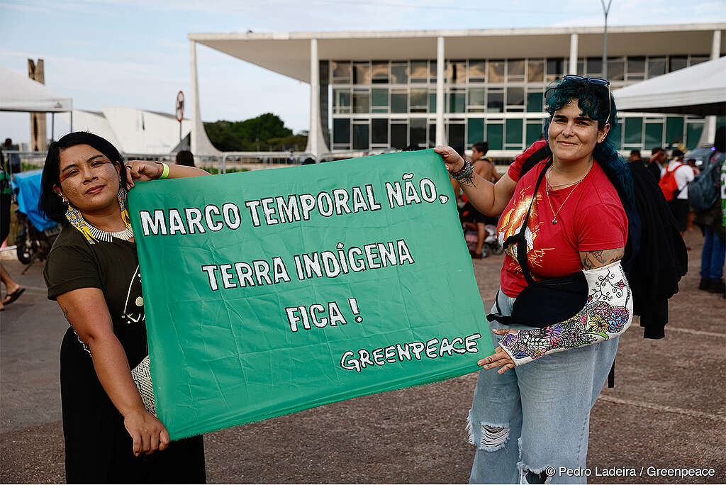 Em um plano aberto, a imagem feita em Brasília mostra duas mulheres segurando um banner que diz "Marco Temporal Não, Terra Indígena fica!"
