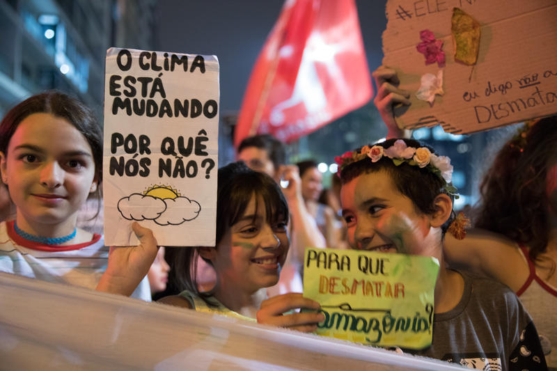 meninas jovens seguram cartaz "Se o clima está mudando, por que nós não?