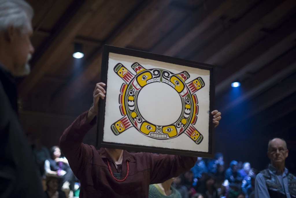 Greenpeace's Eduardo Sousa holds renewed Sisutl Symbol by Kwakwaka'wakw artist Beau Dick, with Greenpeace founder and original 1971 crew member Bill Darnell looking on (to the right)