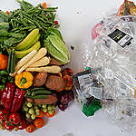 Plastic packaging next to fruit and vegetables.