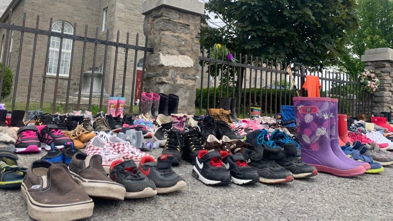 Des chaussures d'enfants ont été placées devant une église de Kahnawake, en mémoire des 215 enfants dont les restes ont été retrouvés sur le site du pensionnat de Kamloops, en Colombie-Britannique. (Chloe Ranaldi/CBC)