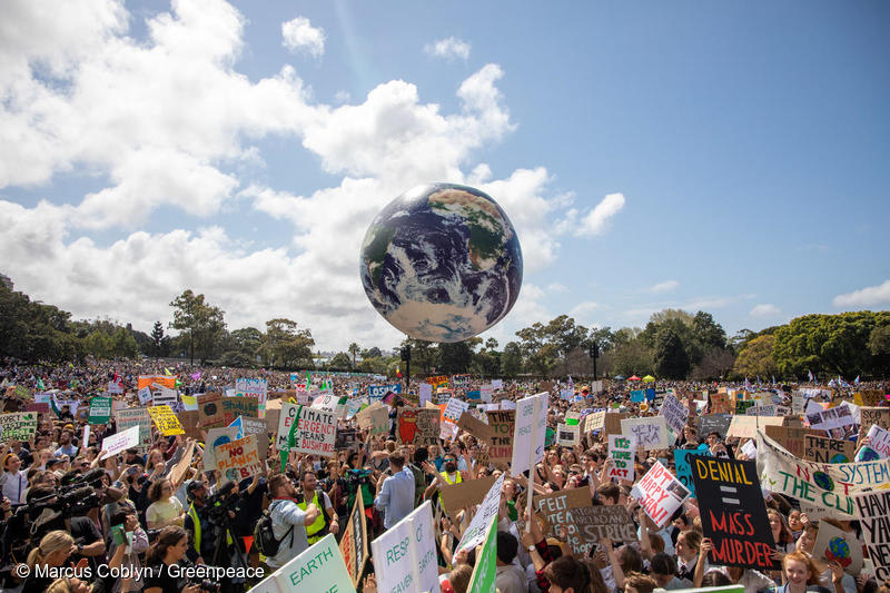 Una multitud juega con un globo terráqueo en la marcha por el clima de Sydney.