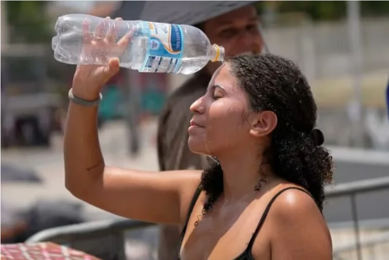 Mujer se refresca el rostro utilizando una botella con agua. Mujer se refresca el rostro utilizando una botella con agua.