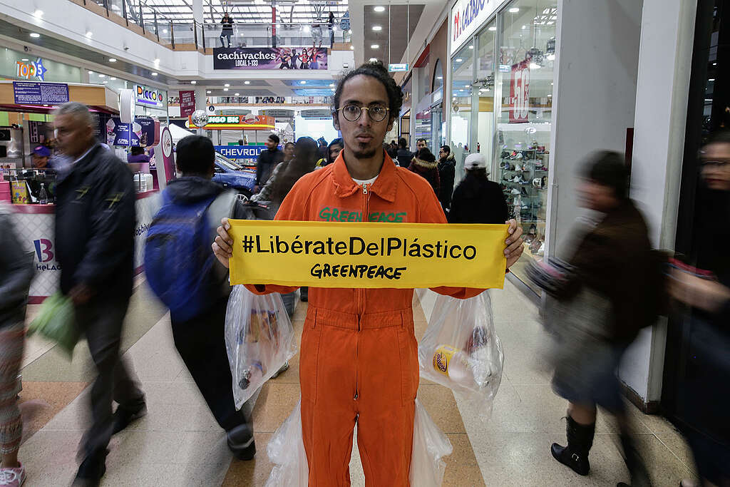 Activista de Greenpeace con una cartel parado en un centro comercial con un cartel en sus manos: Lib&eacute;rate del Pl&aacute;stico.