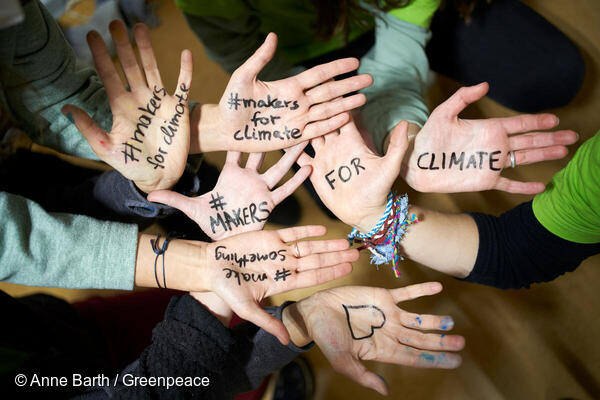 Mange hænder med budskaber for bedre klima skrevet med tusch.