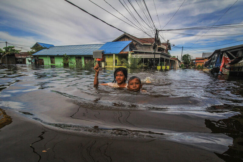 To børn svømmer i vandmasserne ved oversvømmelse i Palangka Raya i Indonesien.