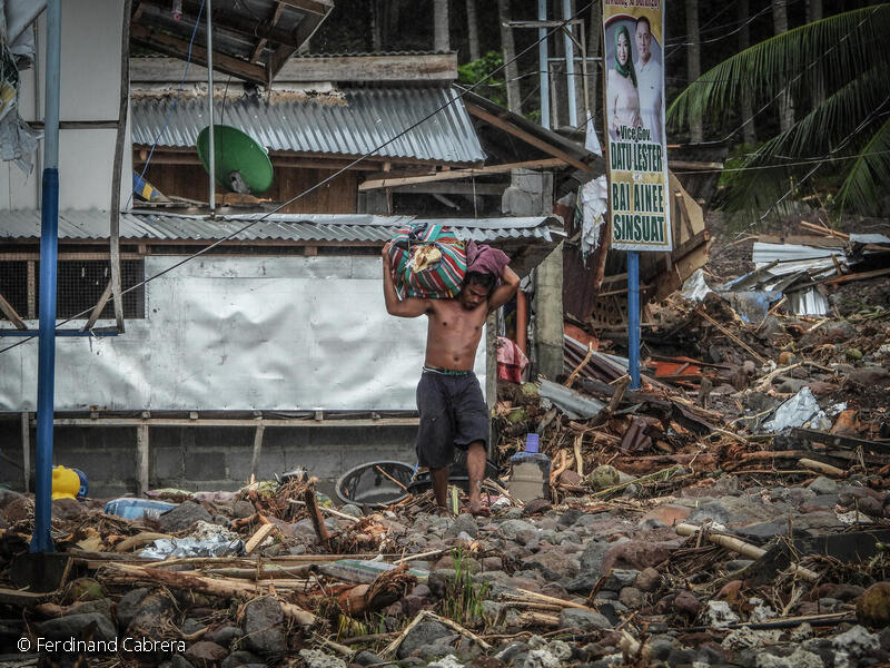 En mand bærer resterne af sit hjem på skulderen, efter en ekstremt vejr har hærget Filippinerne.