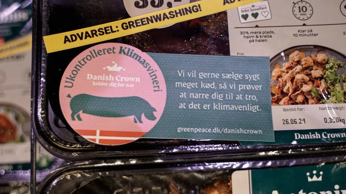 EN kødpakke i en køledisk, der har fået et klistermærke med en advarsel på greenwashing på.