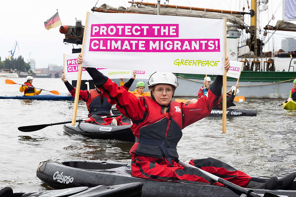 Women in a kayak demonstrating and holding a Greenpeace banner with the text "Protect the climate migrants!".