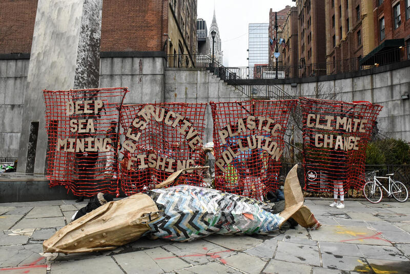 Greenpeace USA aktivister og lokale kunstere demonstrerer foran FN-bygningen i New York. På bannerne står der blandt andet "dybhavs minedrift" og "destruktivt fiskeri". 
 