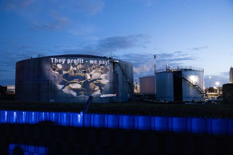 Greenpeace-aktivister projicerede i september 2026 beskeden “De tjener, vi betaler” op på et brændstoflager på Hamborg Havn.