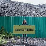 Greenpeace Campaigner, Hall Sion Chan, is putting up a banner written "Waste No More, Adequate Housing Now" in front of a few storey high waste mountain at Ha Tsuen, Hong Kong, urging the Government to seriously review the brownfield planning policy. © Greenpeace / Harry Long