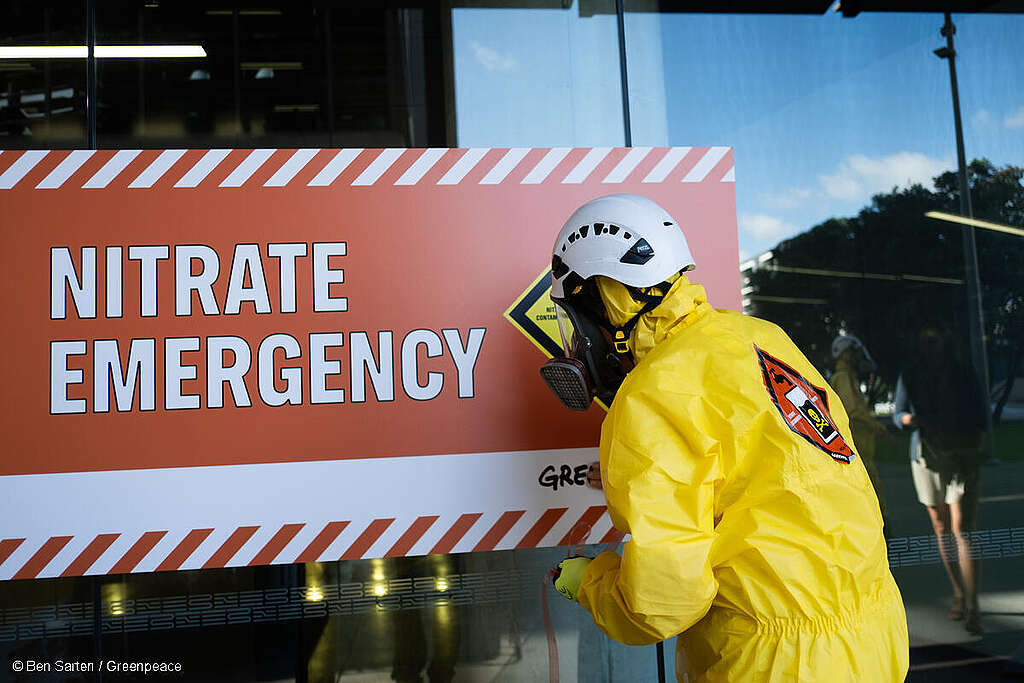 A Greenpeace activist installs a sign reading "Nitrate Emergency" in Auckland, Aotearoa New Zealand 2022.