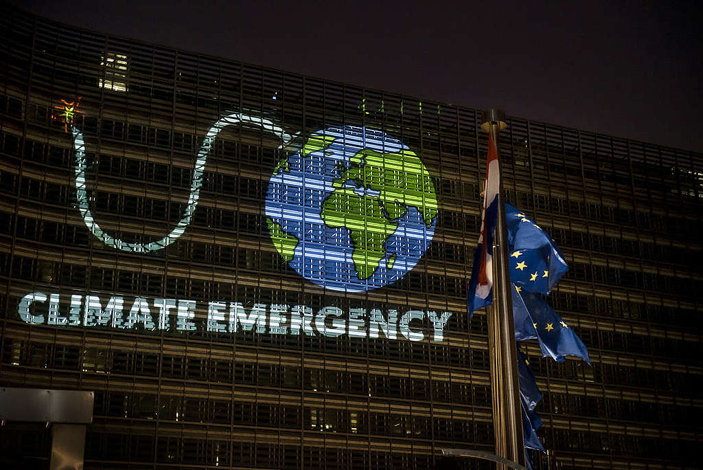 Greenpeace heijasti EU:n päämajan seinään Kuvan maapallosta, jossa on kiinni palava sytytyslanka. Kuvan alapuolella on teksti Climate emergency.