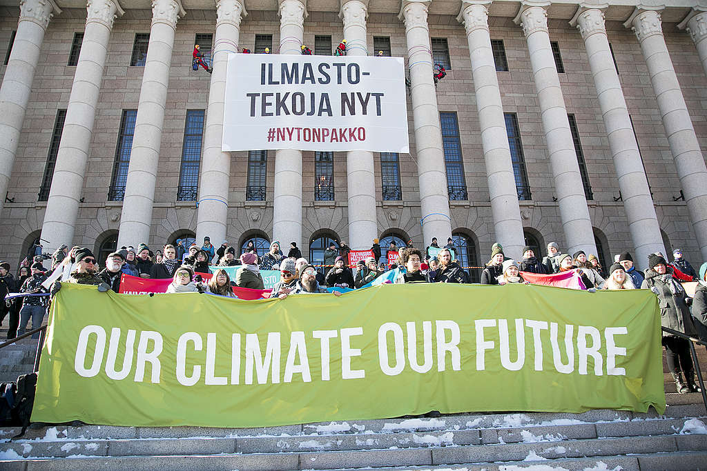 Ilmastomielenosoitus eduskuntatalon portailla. Eduskuntatalon pylväisiin on kiivennyt Greenpeacen aktivisteja, jotka ovat ripustaneet banderollin, jossa lukee "ilmastotekoja nyt" ja "#nytonpakko".