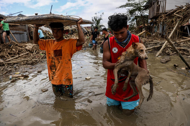 Mies kantaa koiraansa tulvivalla kadulla Rodriquezin kaupungissa