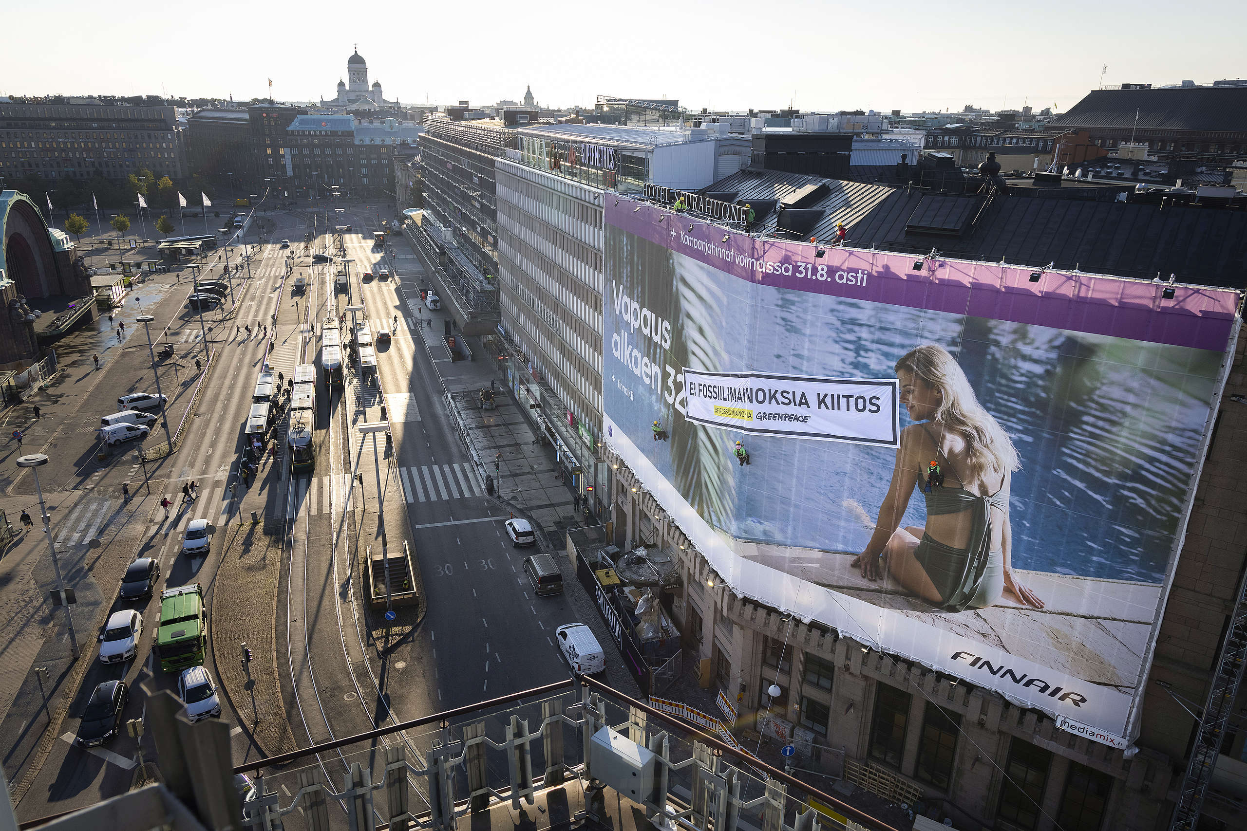 Greenpeacen aktivistit ripustivat fossiilimainontaa vastustavan banderollin Finnairin mainoksen päälle Helsingin Kaivokadulla 30.8.2021
