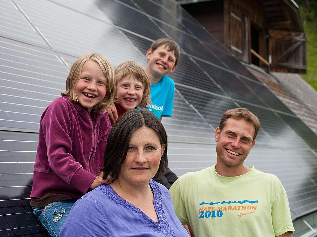 Sveitsiläinen maanviljeliäperhe aurinkopaneelien päällä.