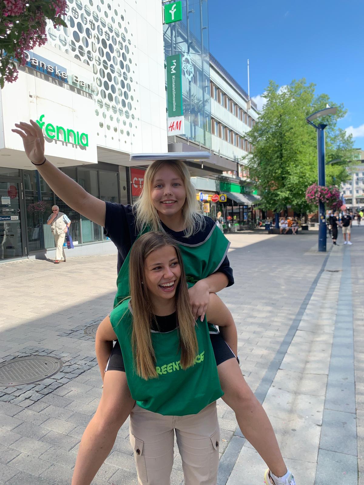 Kaksi Greenpeacen feissareita, joista toinen on toisen reppuselässä.