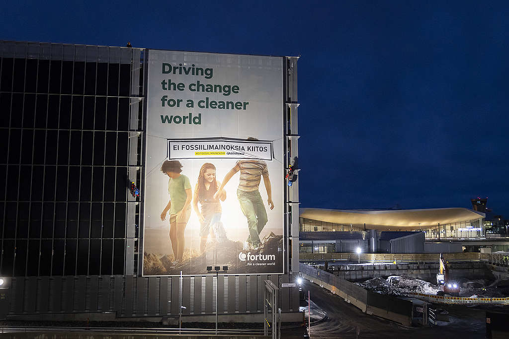 Greenpeacen aktivistit laittoivat oman banderollinsa Fortumin mainoksen päälle. Fortumin mainoksessa lukee "Driving the change for a cleaner world" ja GP:n banderollissa "Ei fossiilimainoksia, kiitos".