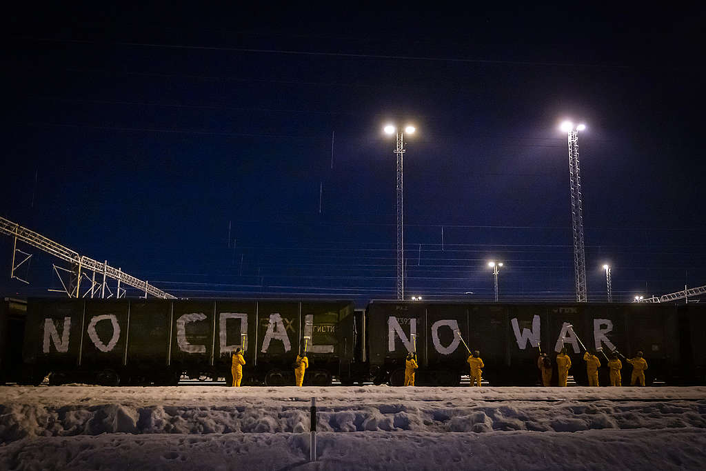 Greenpeacen aktivistit maalaamassa junaradan varrelle tekstiä "NO COAL NO WAR"