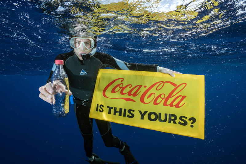 Greenpeacen aktivisti merestä löytämänsä Coca-Cola-pullon kanssa.