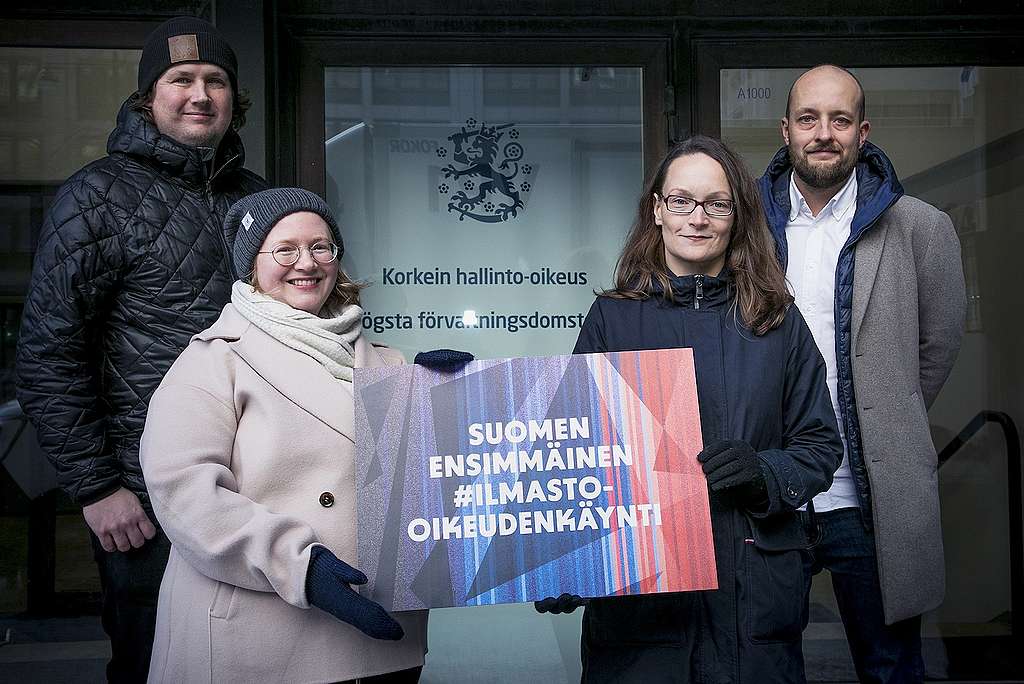 Greenpeacen ja Suomen luonnonsoujeluliiton edustajat pitelevät Korkeimman hallinto-oikeuden edessä kylttiä, jossa lukee "Suomen ensimmäinen ilmasto-oikeudenkäynti".