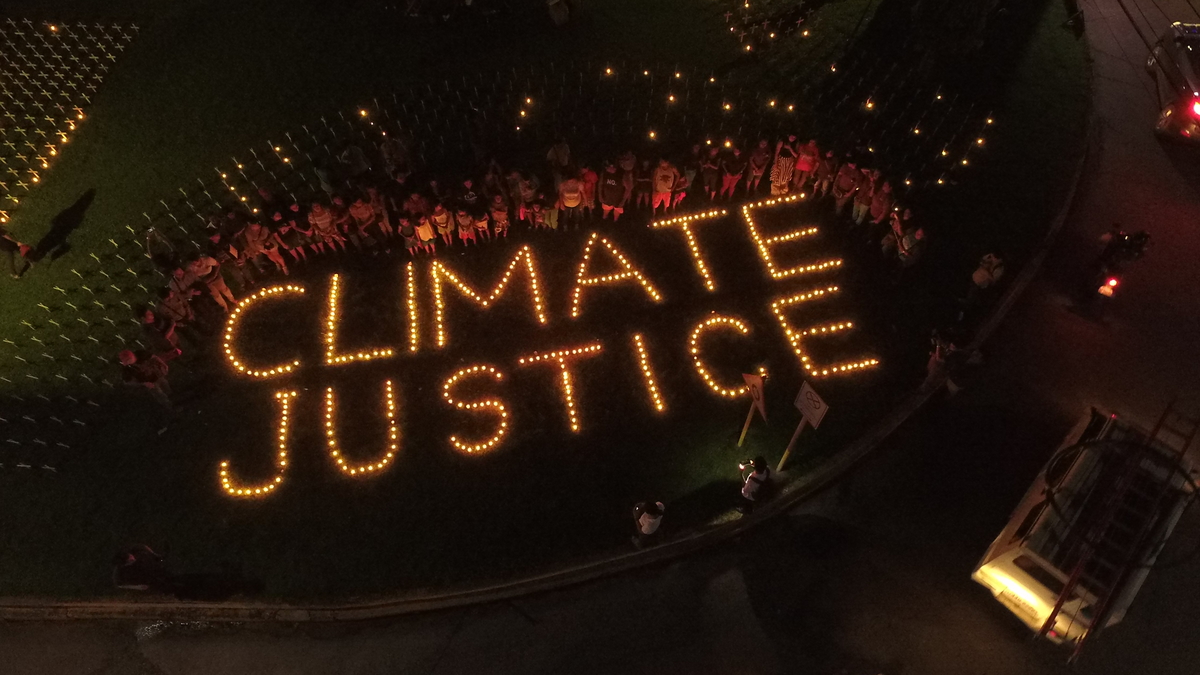Soihtumielenosoitus, jossa soihduilla muodosteaan sanat "climate justice".