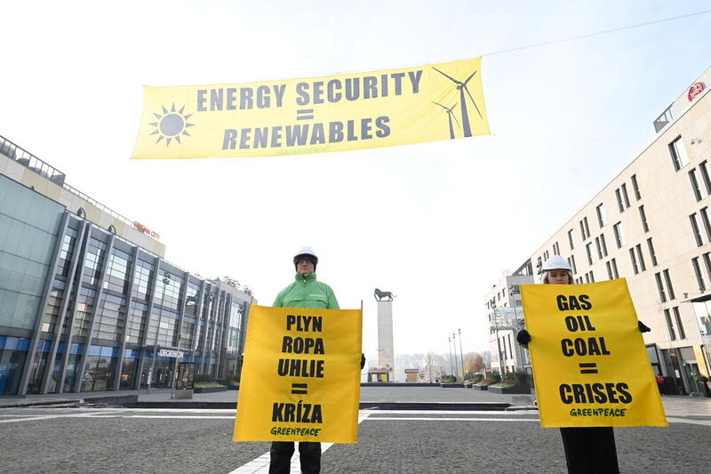 Kuvassa kaksi Greenpeacen aktivistia osittavat mieltä banderollien kanssa. Banderolleissa lukee "GAS, OIL, COAL =CRISES". Taustalla myös isompi banderolli, jossa lukee "ENERGY SECURITY=RENEWABLES".