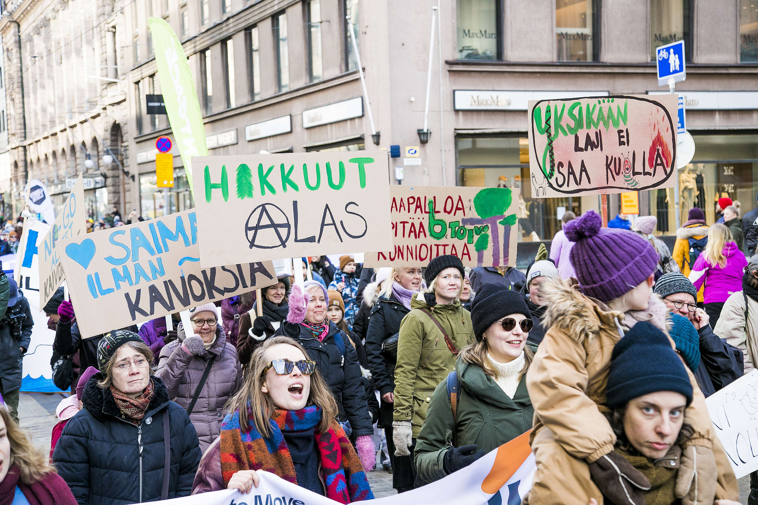 Mielenosoittajia luontomarssilla Aleksanterinkadulla. Mielenosoittajien kylteissä on terveisiä vaalivoittajille.
