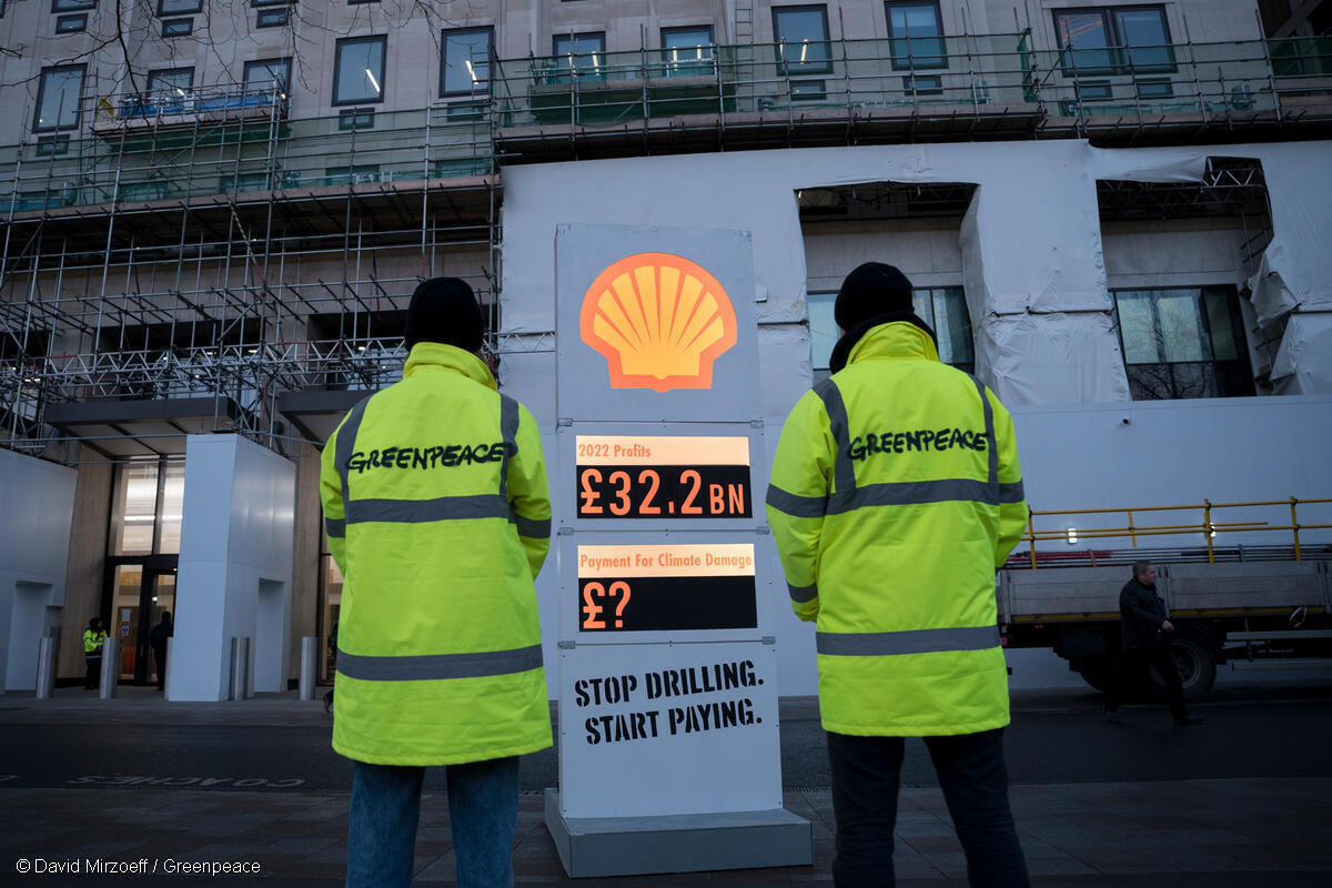 Greenpeacen aktivistit katsovat selin Shellin bensan hintakylttiä muistuttavaa kylttiä, jossa näkyykin esim. Shellin keräämät valtavat voitot.