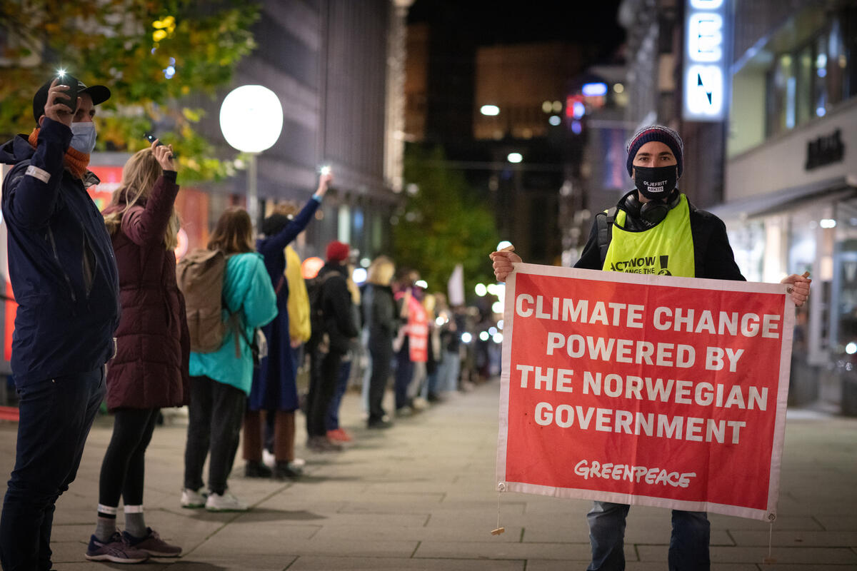 Mielenosoitus Norjan korkiemman oikeuden edessä. Yhdellä mielenosoittajalla on kädessään banderolli, jossa lukee "climate change powered by the norwegian gevernment".