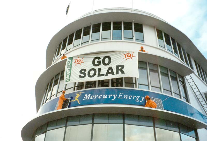 March 1998: Greenpeace urges Mercury Energy to ‘Go Solar - Greenpeace NZ activists Carmen Gravatt and Steve Abel hang banner on Mercury Energy Auckland HQ. Photo by Michael Szabo
