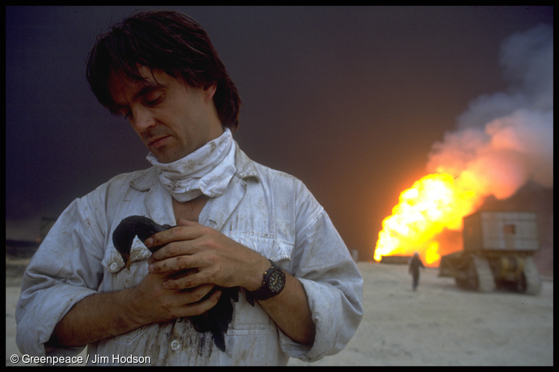 Greenpeace Climate Campaigner Paul Horsman holding an oiled bird near a burning oil well in the aftermath of the first Gulf War in 1991