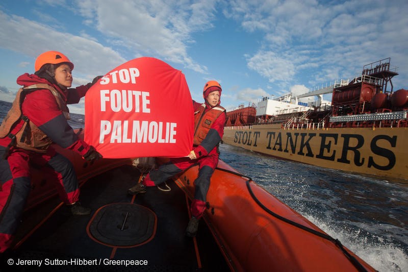 Waya (on left) - activist from Indonesia, and Victoria (on right) activist from Canada, from the Greenpeace ship MY Esperanza, hold banners protesting dirty palm oil beside the Stolt Tenacity tanker ship which is carrying dirty palm oil from Indonesia to Rotterdam, in the Atlantic Ocean, on 21 November 2018.