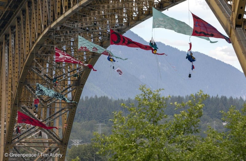 Activist form an aerial bridge blockade in the path of a Trans Mountain tar sands oil tanker traffic. The tar sands oil tanker was docked at the Kinder Morgan’s Westridge Marine Terminal. The blockade is part of wave of growing resistance against the controversial Trans Mountain Expansion pipeline and tanker project (TMX). The activists suspended from the Iron Workers Memorial Bridge in Vancouver, British Columbia.