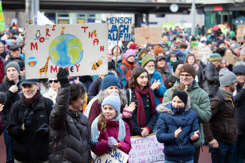 遊行人士舉起標語，寫著：「More than money」，意指金錢事小，地球生態與人類安危才事大。© Kristian Buus / Strike WEF