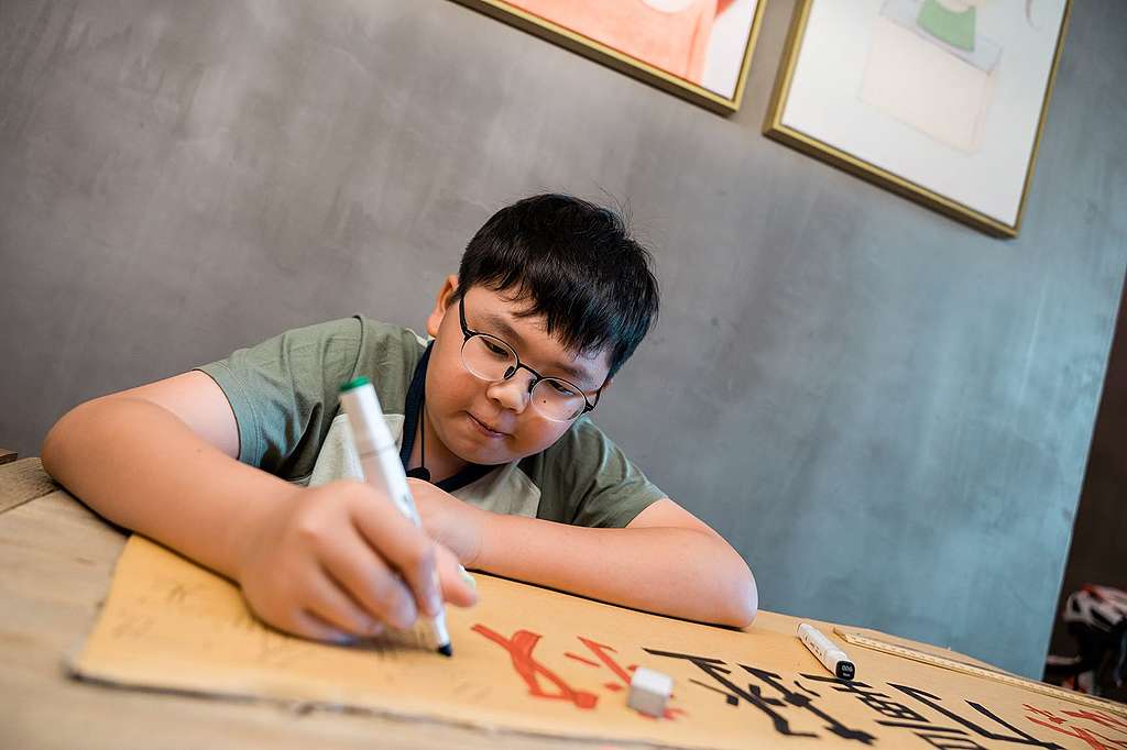 Lance製作氣候標語,計算紙板的長度、標語字數,然後作美術發揮。正正是糅合他對視藝和科學的喜好。© Patrick Cho/Greenpeace