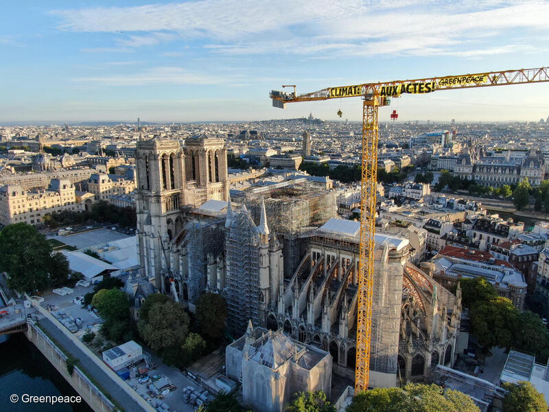 法國巴黎：行動者在巴黎聖母院旁進行直接行動，爬上近20米高的起重重機吊臂，展示「氣候：立即行動！」橫額。© Greenpeace