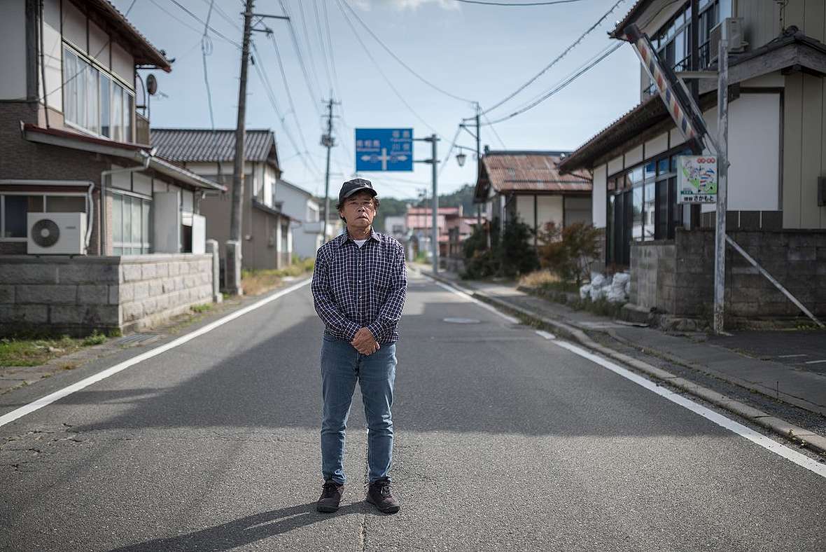 安西先生站在飯館村空蕩的街道，村在福島第一核電廠西北約30-40公里，10年前是嚴重的核污染災區。一場核災抹掉往昔的鄉情。© Christian Åslund / Greenpeace