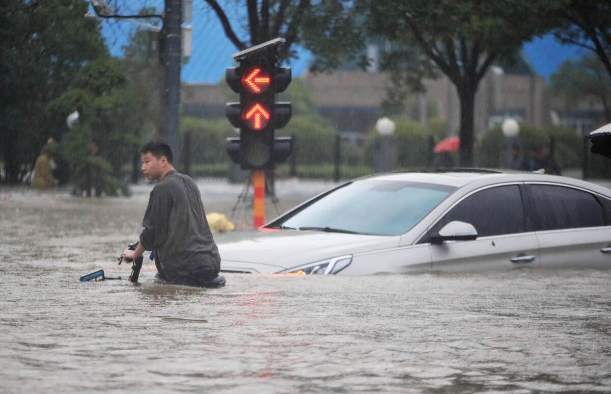 2021年7月中國鄭州遭遇暴雨，大路上市民推著單車，水面高至腰間。© visual.people