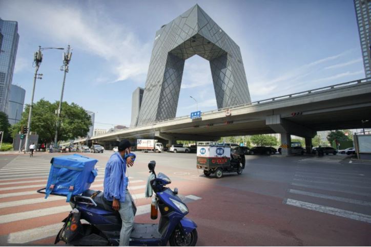 2020年6月北京，速遞員在交匯處等候交通燈，選擇在建築蔭蔽地方避熱。© Yan Tu/Greenpeace