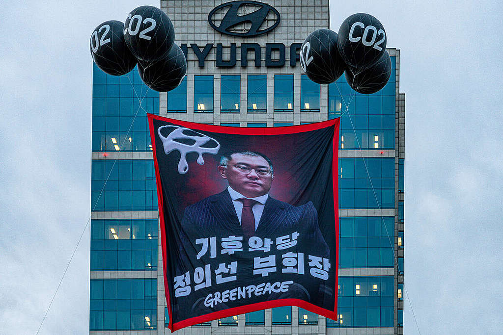 2020年9月，首爾辦公室行動者在現代汽車總部大樓外以「碳排放」汽球懸起會長鄭義宣的肖像橫額，促請對方兌現承諾加速淘汰燃油車。 © Greenpeace / Sungwoo Lee