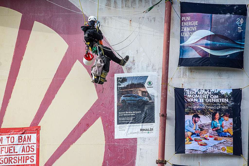2021年10月4日，綠色和平行動者在SHELL位於荷蘭鹿特丹的煉油廠攀上油缸，並在外牆張貼能源企業的「漂綠」廣告，喚起公眾關注。 © Bart Hoogveld / Greenpeace