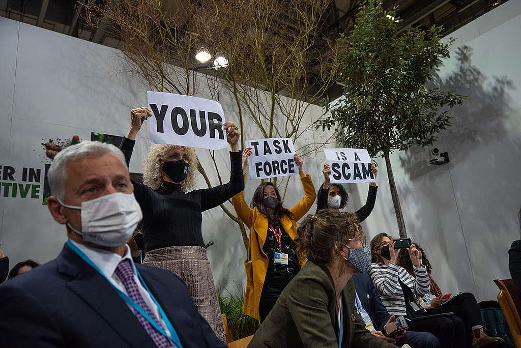 COP26期間，國際綠色和平總幹事Jennifer Morgan（黑衣者）聯同環保團體代表，高舉「你的委員會是一場騙局（YOUR TASKFORCE IS A SCAM）」標語表達抗議。© Przemysław Stefaniak / Greenpeace