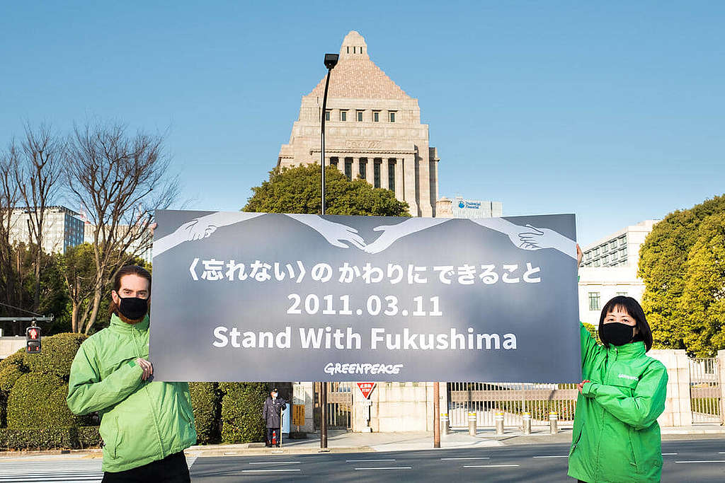 福島核災10周年，綠色和平東京辦公室行動者在國會議事堂外面舉起橫額，呼籲日本政府走向一個使用可再生能源的將來。 © Taishi Takahashi / Greenpeace