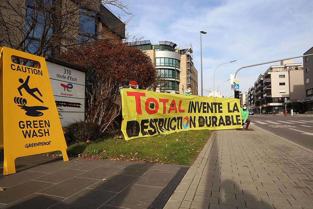 2021年11月，綠色和平行動者於道達爾石油盧森堡分部外展示「小心漂綠」訊息，促請該企業與其大灑金錢投放品牌改造，不如認真實踐能源轉型。 © Greenpeace / Anais Hector