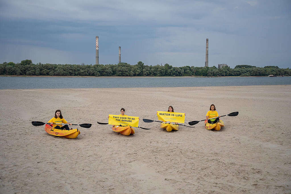 「這裡曾經是多瑙河」、「水是生命泉源」：綠色和平行動者在水位驟降的多瑙河展示標語，促請羅馬尼亞當局減少碳排放，挽救極端氣候。© Răzvan Dima / Greenpeace