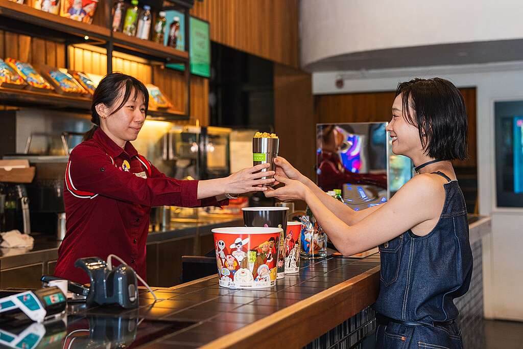 談善言(右)化身綠色和平「愛海洋・有借有還爆谷杯」計劃首批顧客,一嘗以重用杯代替即棄紙杯的體驗。 © Greenpeace